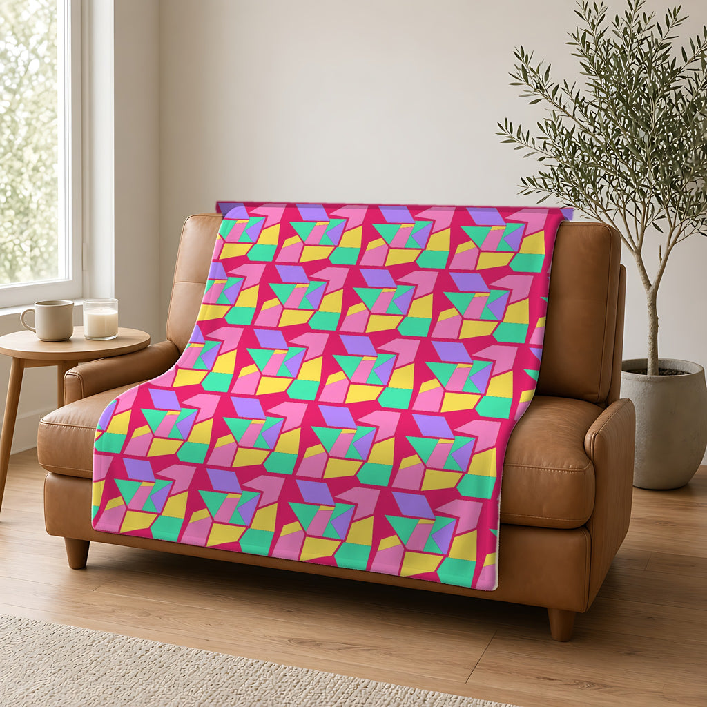 Cubist Block Quilt Sherpa Fleece Blanket draped over a caramel leather sofa