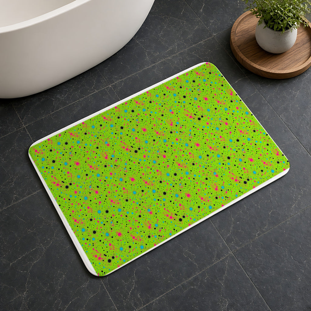 Pink Spray Field Bath Mat on a dark slate floor beside a bath