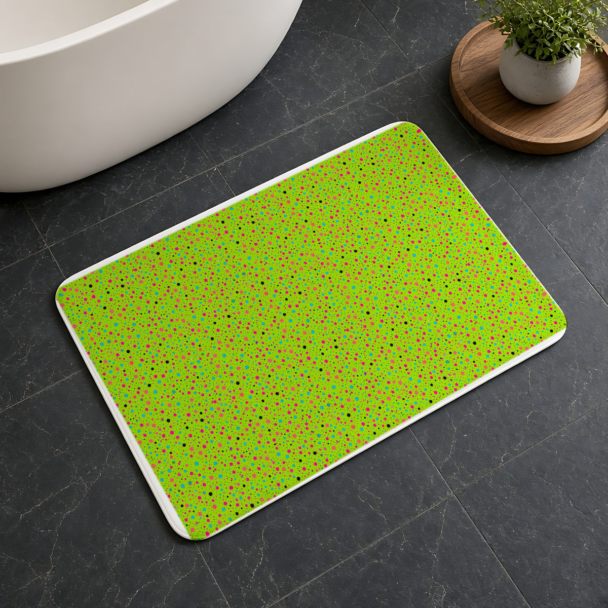 Confetti Spatter Bath Mat on a dark slate floor beside a bath