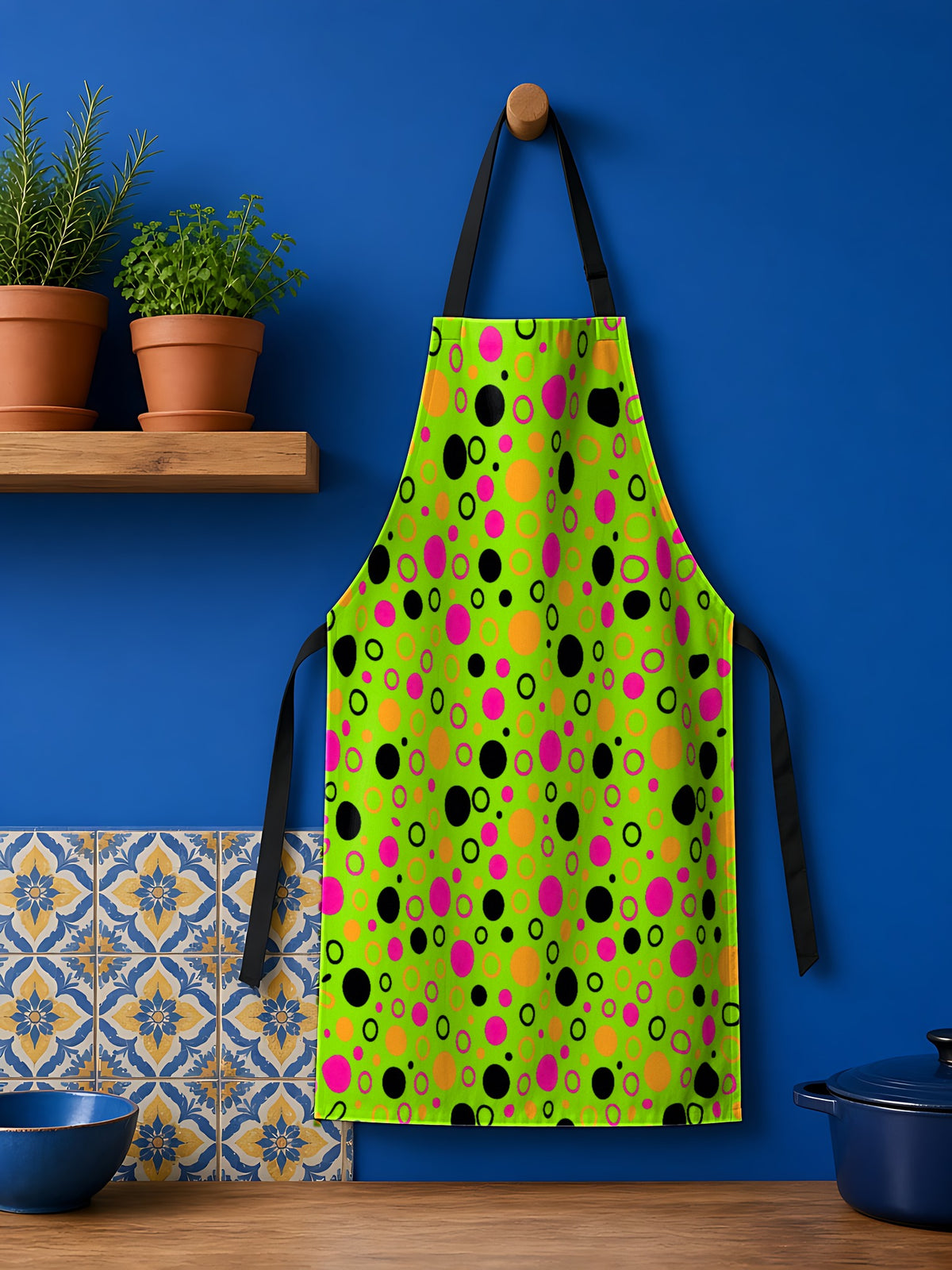 Bubble Outlines Apron in the Tropical Punch palette, hanging against a cobalt-blue kitchen wall