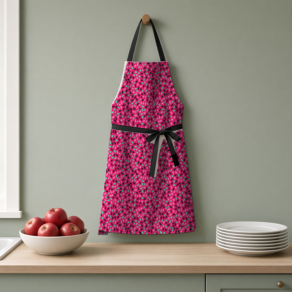 Sprinkle Pop Apron hanging on a sage-green kitchen wall