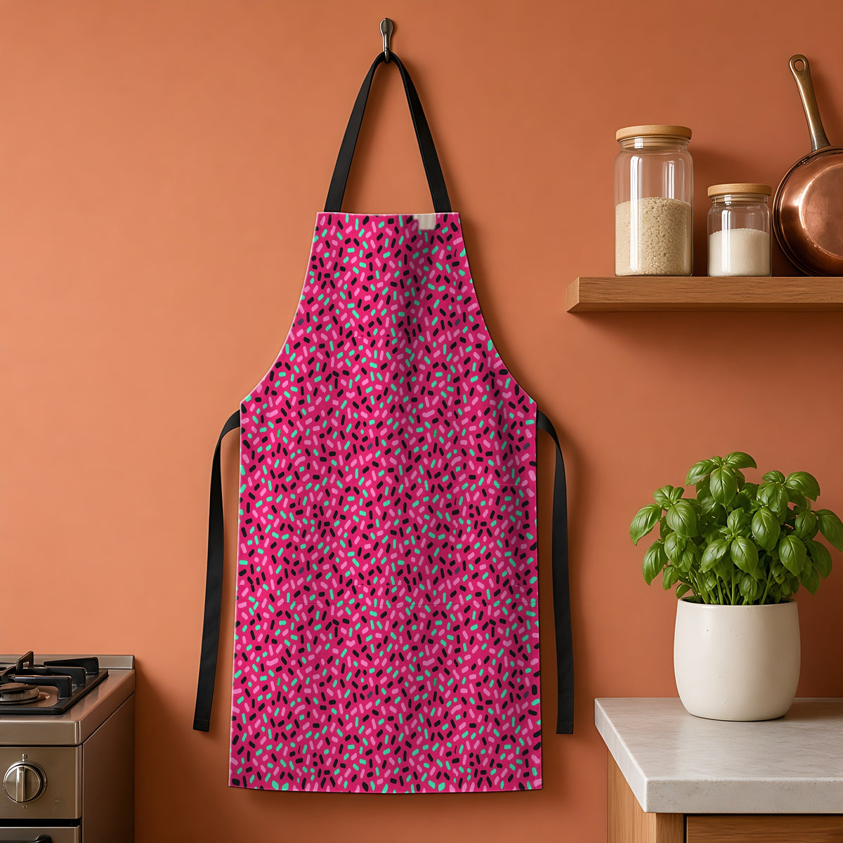 Sprinkle Pop Apron hanging on a terracotta kitchen wall
