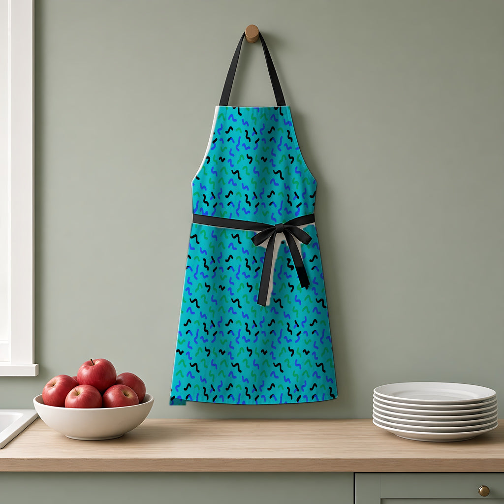 Squiggle Strokes Apron hanging on a sage-green kitchen wall