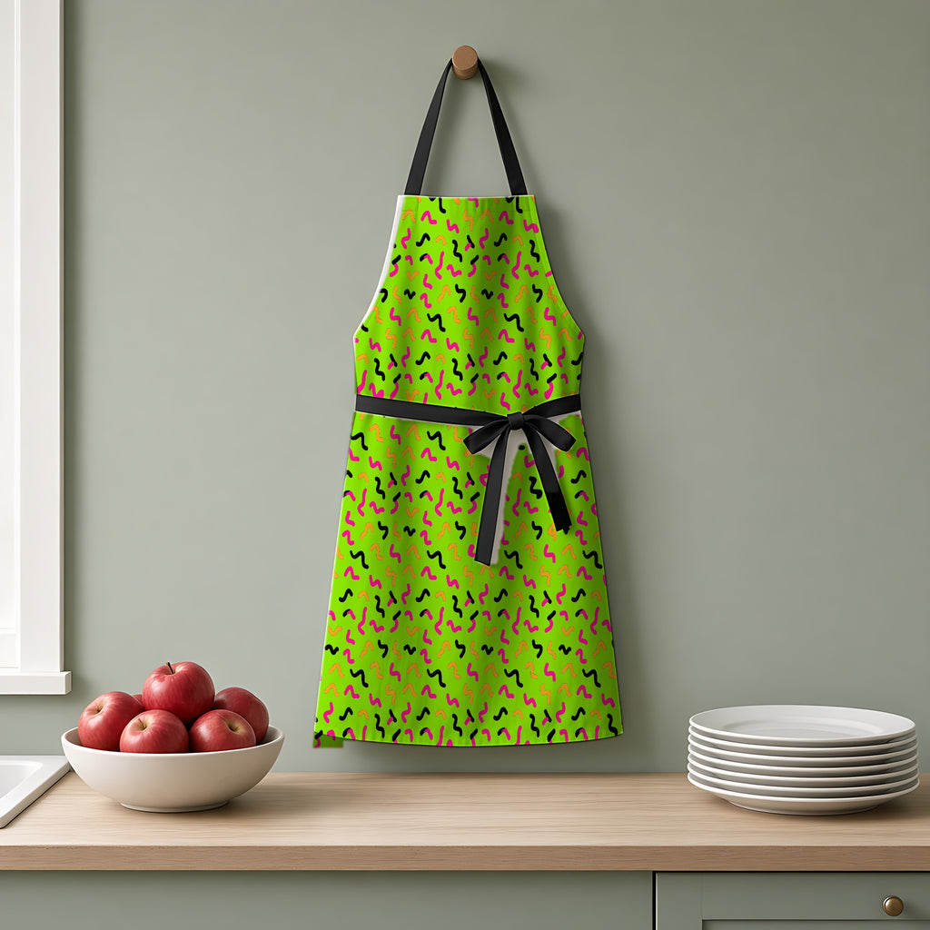 Squiggle Strokes Apron hanging on a sage-green kitchen wall