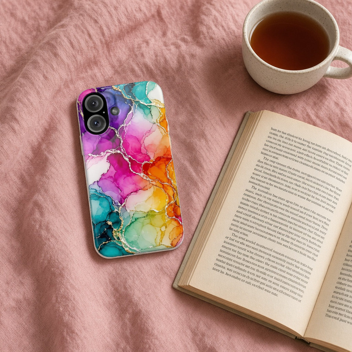 Rainbow Alcohol Ink Bloom slim phone case on a pink bedspread with a book and tea