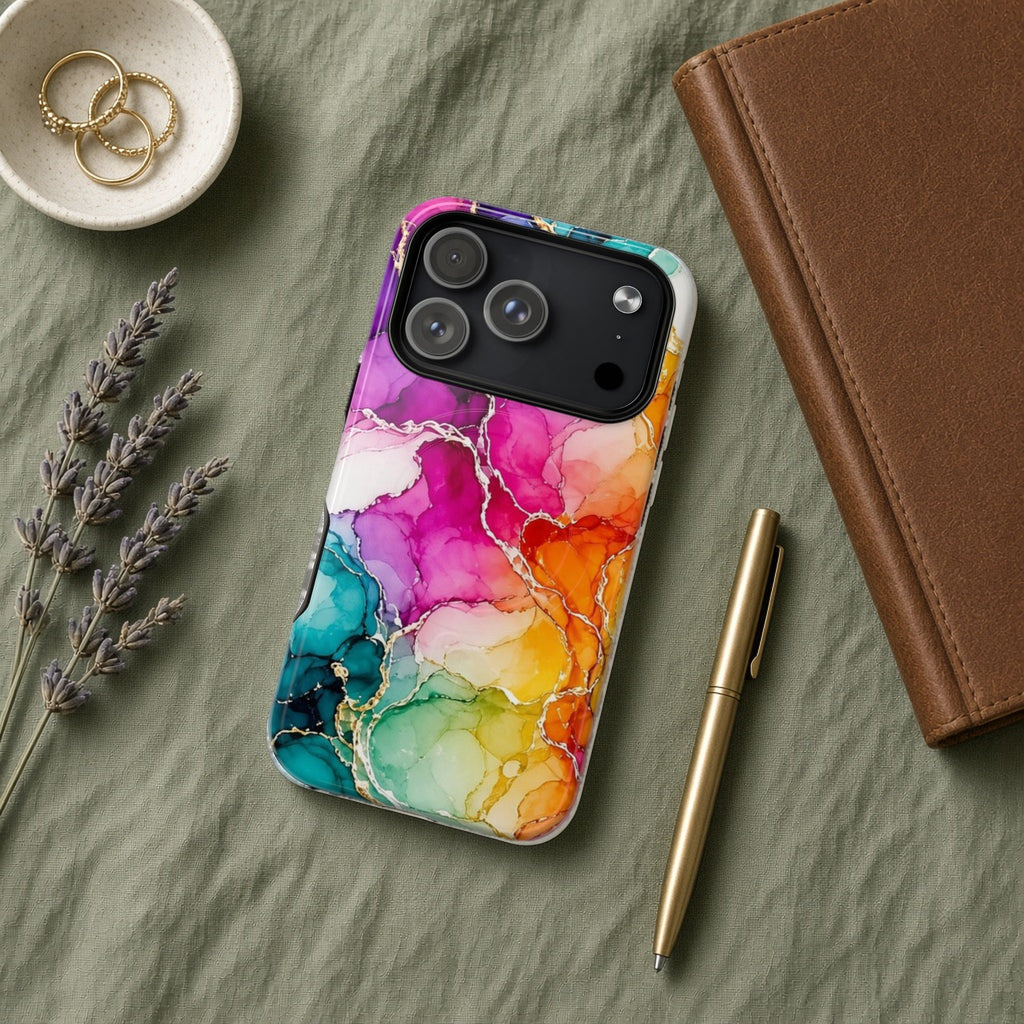 Rainbow Alcohol Ink Bloom magnetic iPhone case flat lay on sage linen with a notebook and pen