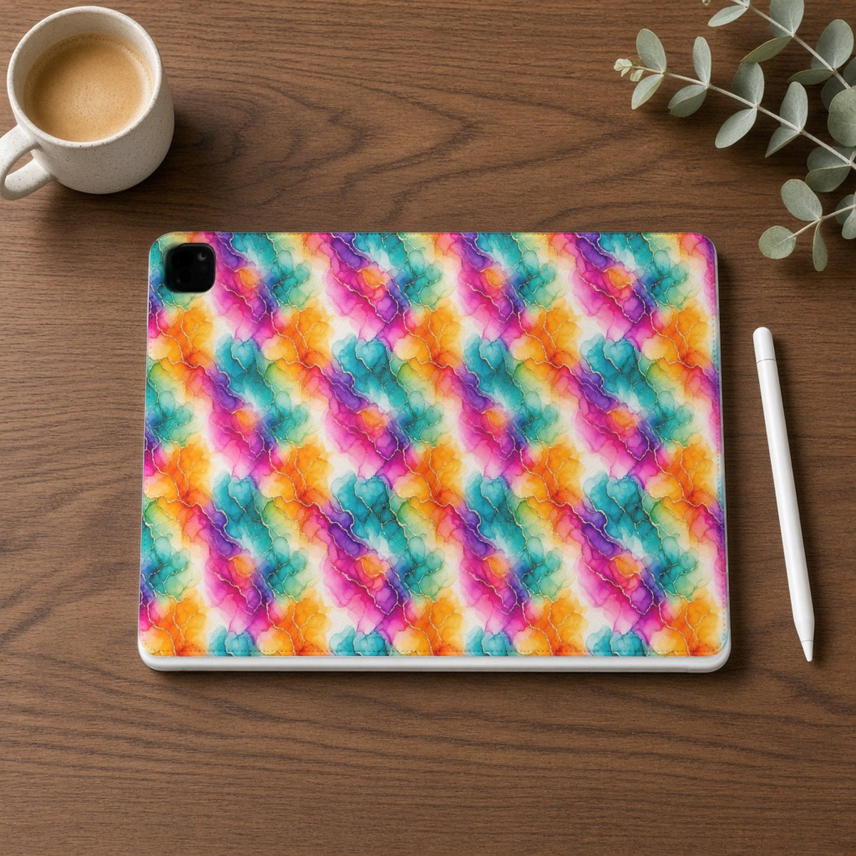 Rainbow Alcohol Ink Bloom iPad folio case on a walnut desk with a stylus and coffee