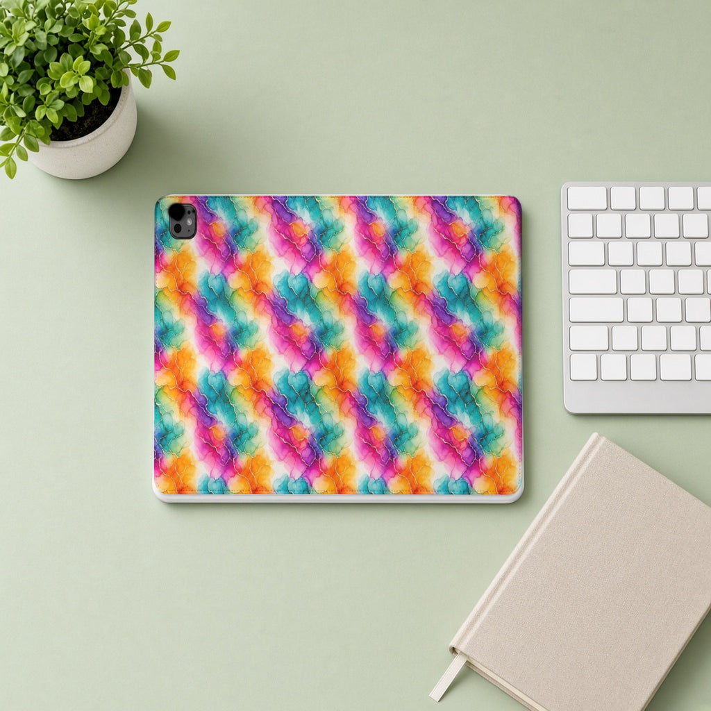 Rainbow Alcohol Ink Bloom iPad folio case from above on a sage desk with a keyboard and notebook