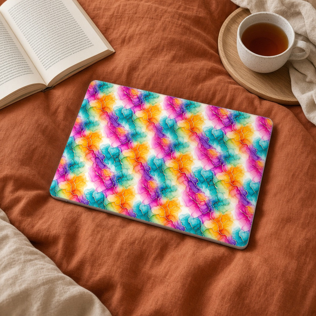 Rainbow Alcohol Ink Bloom matte MacBook case on a laptop on rust linen bedding