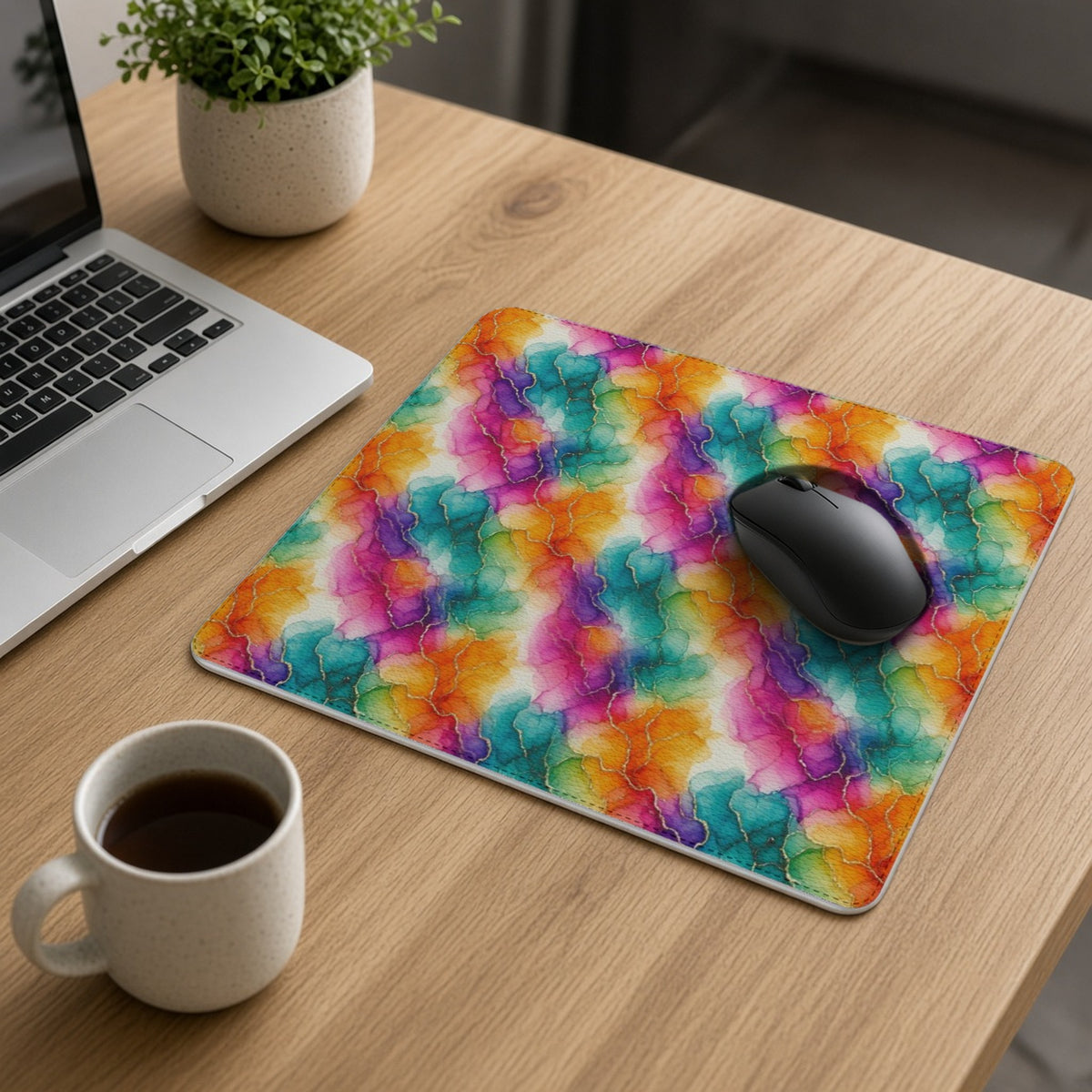 Rainbow Alcohol Ink Bloom vegan leather mouse mat on an oak desk with a laptop, mouse and coffee