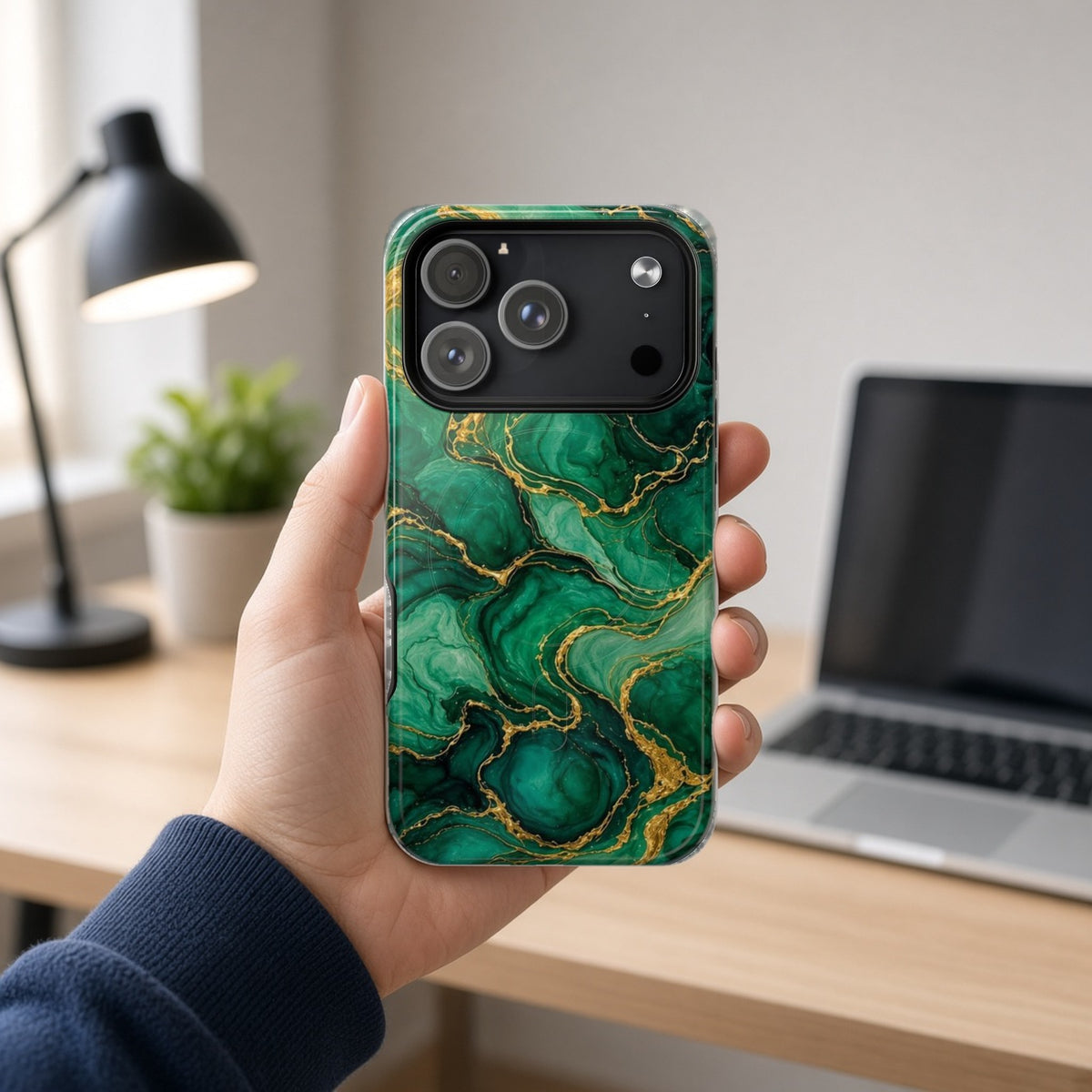 Hand holding the Emerald Tide-Pool Pour magnetic iPhone case at a home office desk