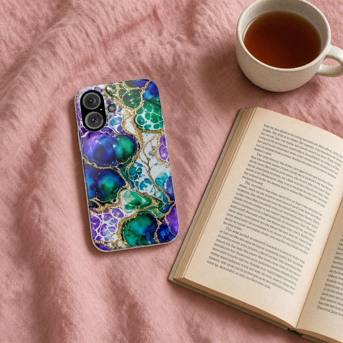 Peacock Acrylic Pour Cells slim phone case on a pink bedspread with a book and tea