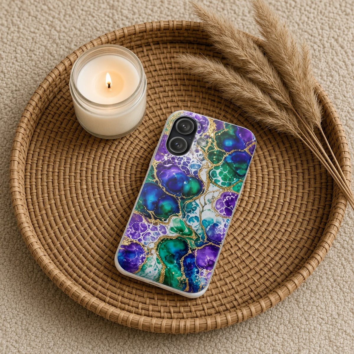 Peacock Acrylic Pour Cells flexi phone case on a rattan tray with a candle and dried grasses