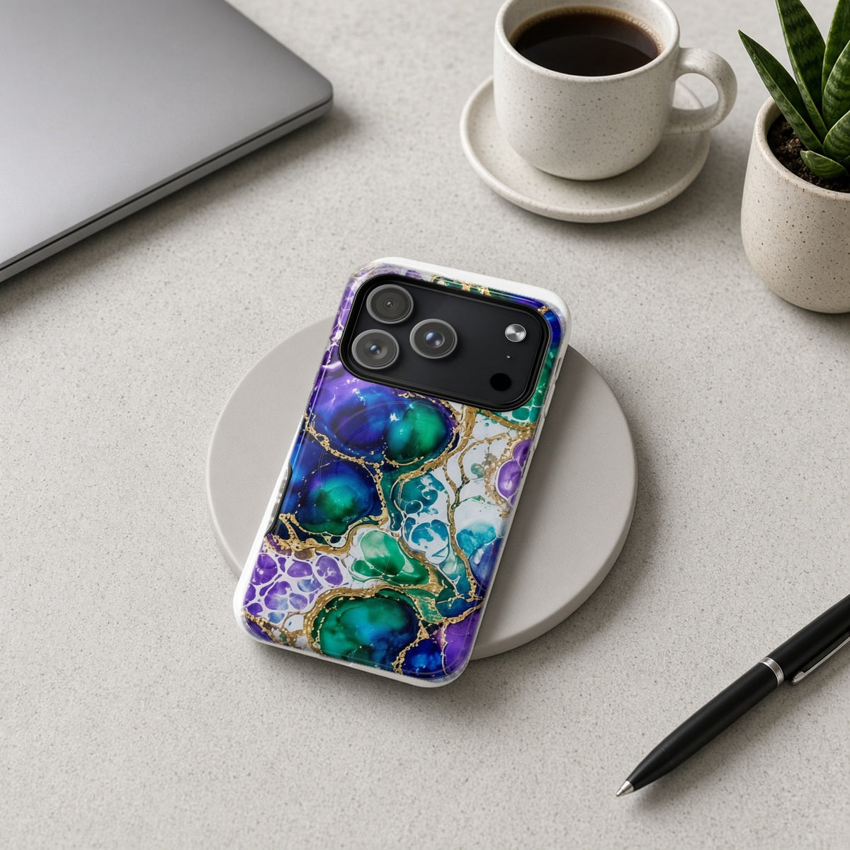 Peacock Acrylic Pour Cells magnetic iPhone case on a wireless charging pad on a grey desk