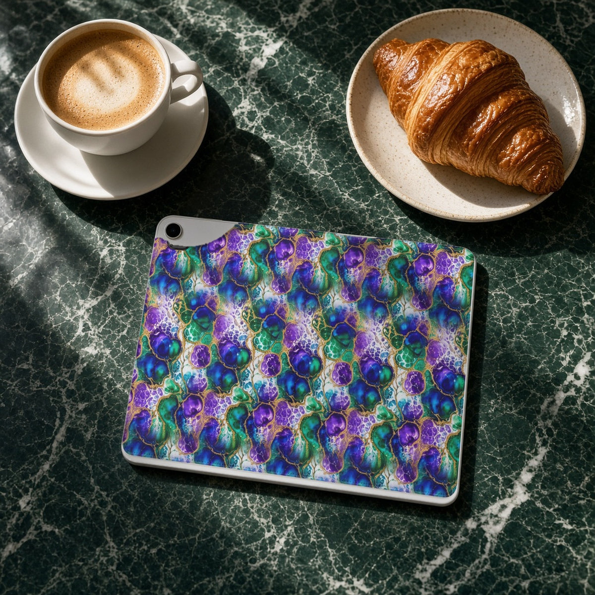 Peacock Acrylic Pour Cells iPad folio case on a green marble cafe table with a cappuccino