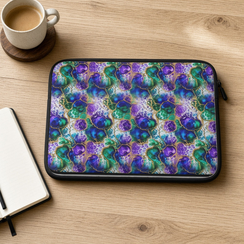 Peacock Acrylic Pour Cells laptop sleeve on an oak desk with coffee and a notebook
