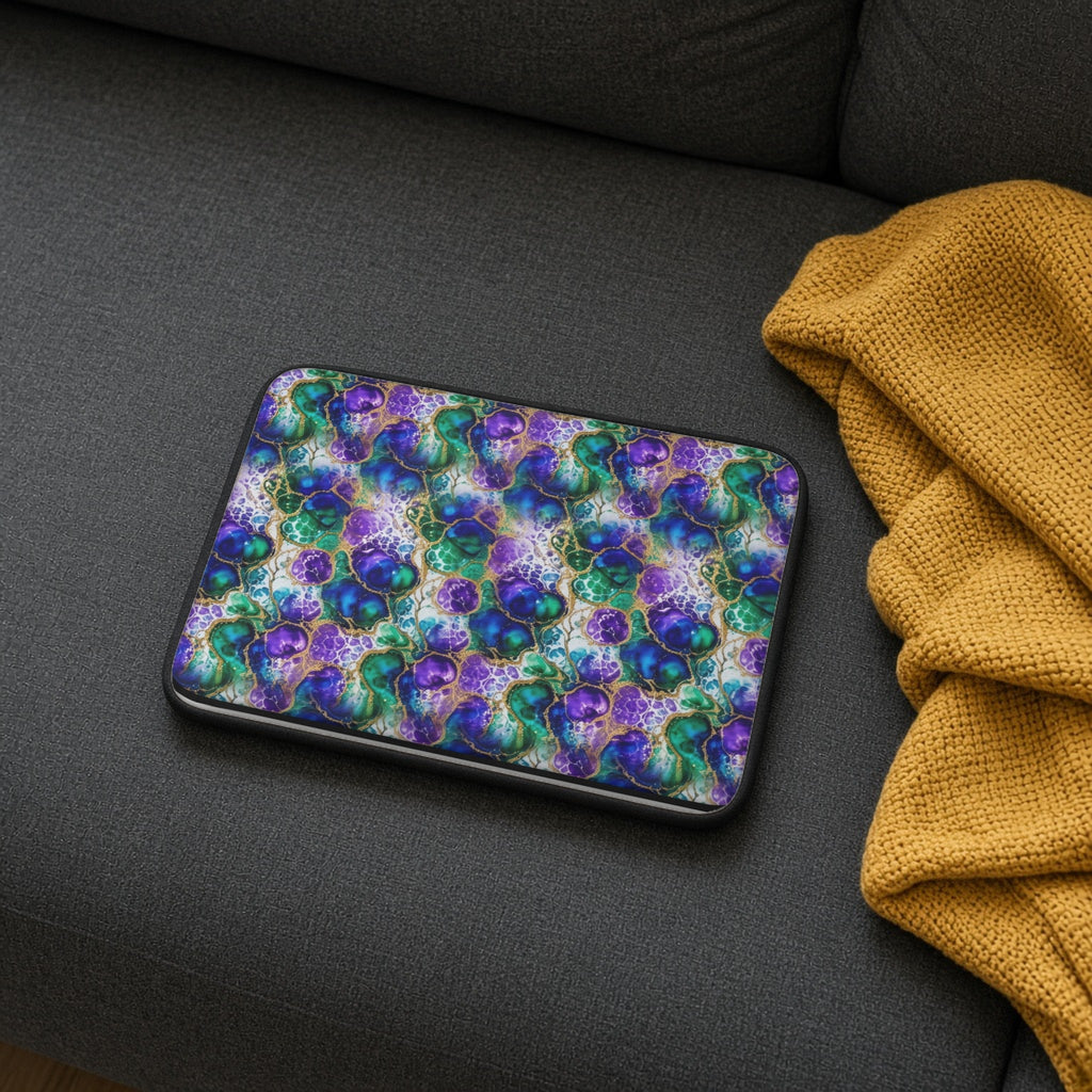 Peacock Acrylic Pour Cells laptop sleeve on a charcoal sofa with a cosy throw