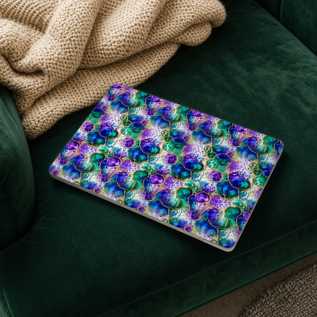 Peacock Acrylic Pour Cells matte MacBook case on a laptop resting on a green velvet sofa
