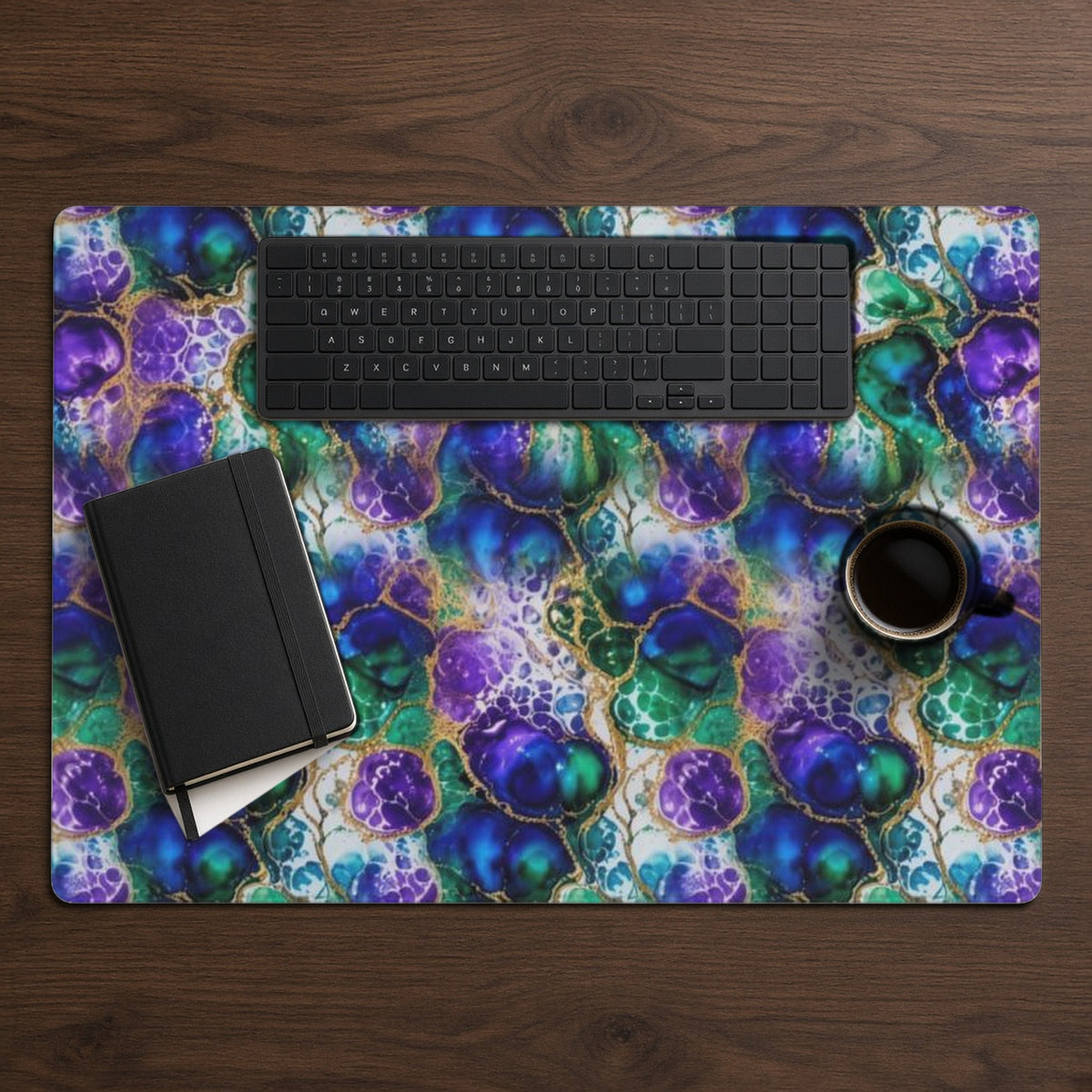 Peacock Acrylic Pour Cells desk mat from above on walnut with a black keyboard, notebook and coffee