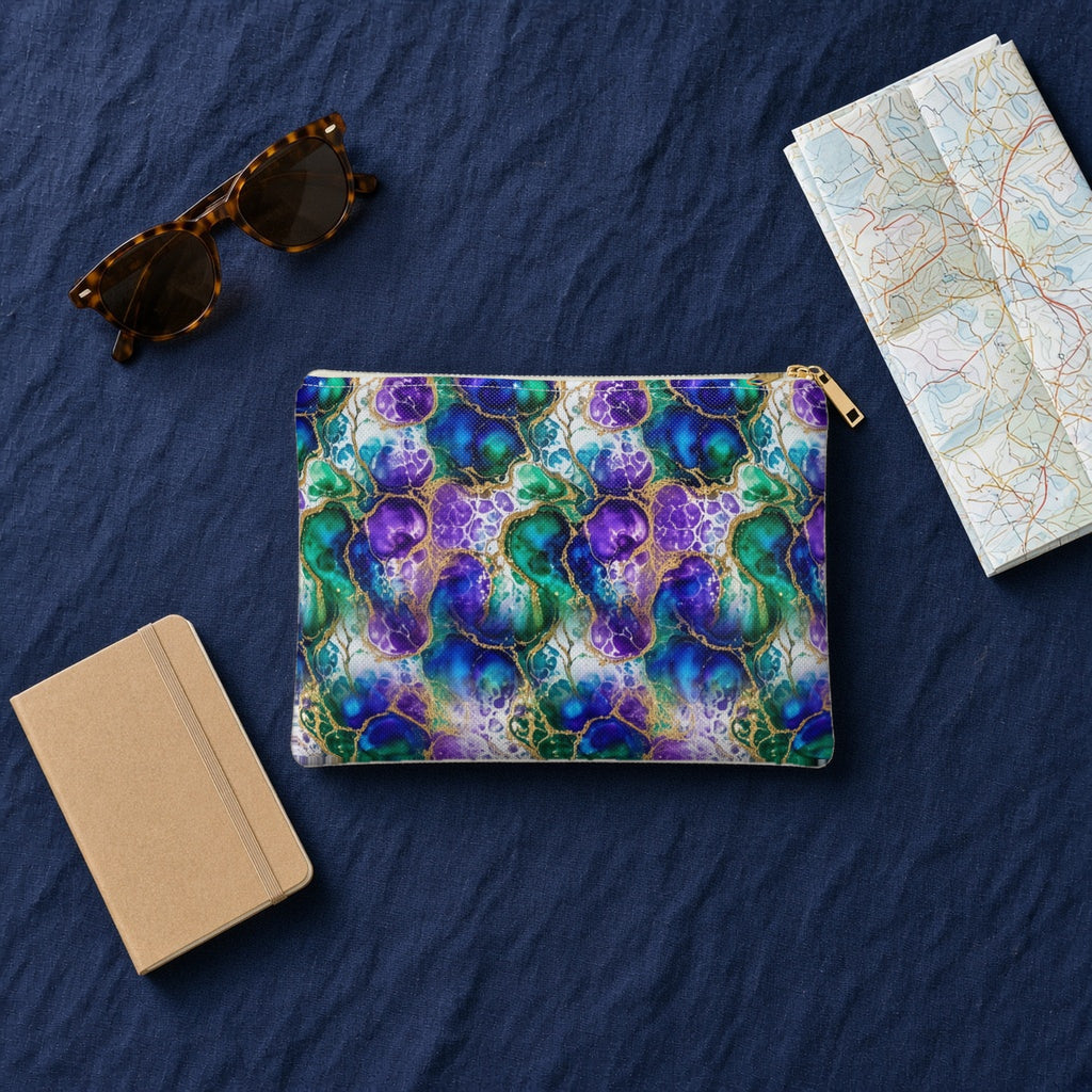 Peacock Acrylic Pour Cells zip accessory pouch on navy linen with sunglasses, a notebook and map
