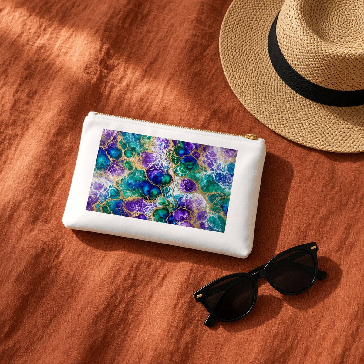 Peacock Acrylic Pour Cells canvas cosmetic bag on terracotta linen with a sun hat and sunglasses