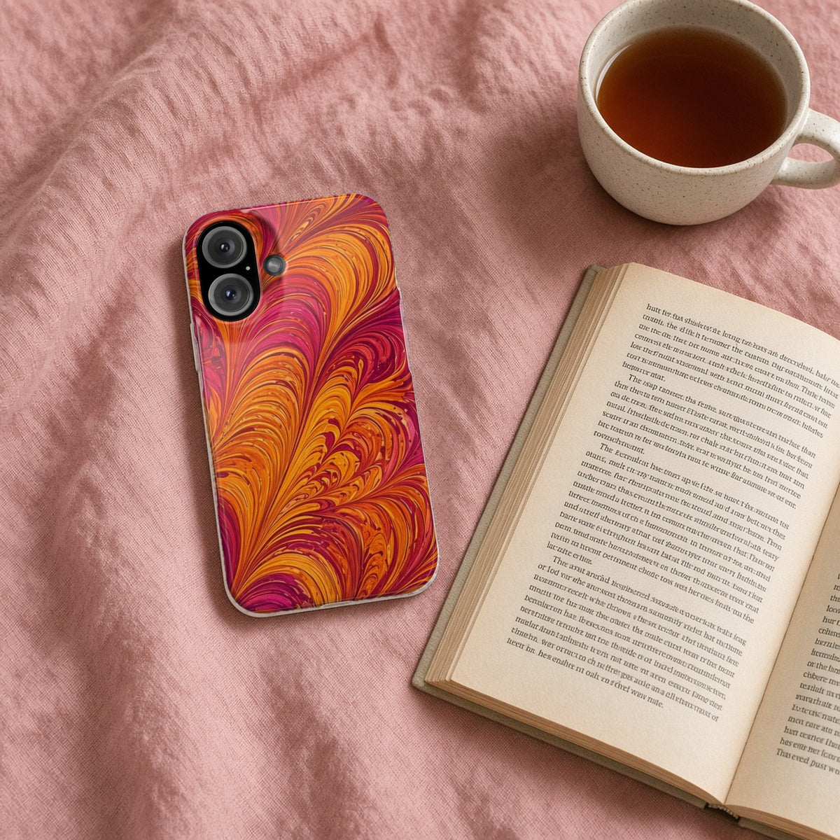 Sunset Feather Marbling slim phone case on a pink bedspread with a book and tea
