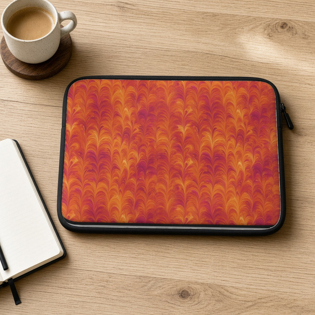 Sunset Feather Marbling laptop sleeve on an oak desk with coffee and a notebook