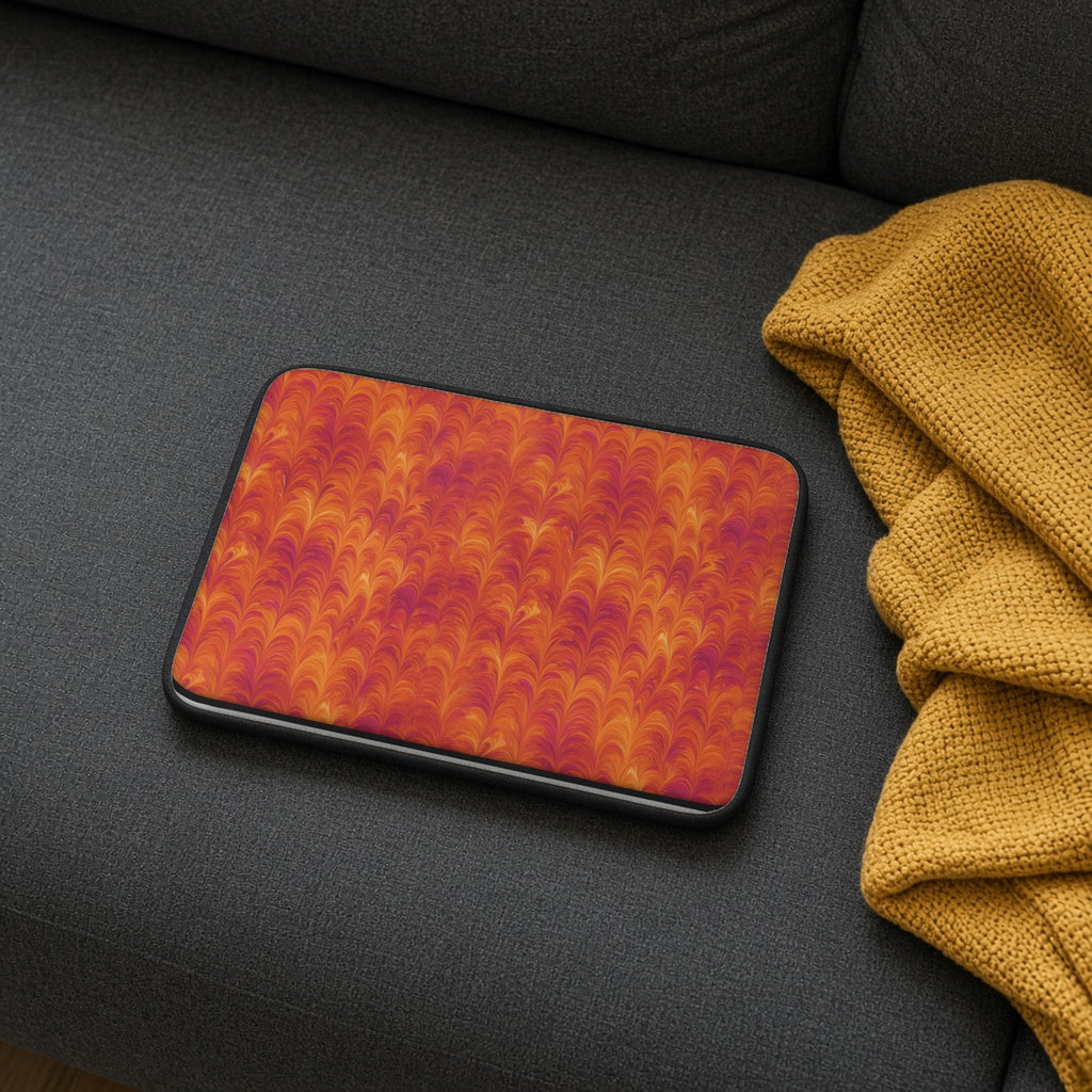 Sunset Feather Marbling laptop sleeve on a charcoal sofa with a cosy throw