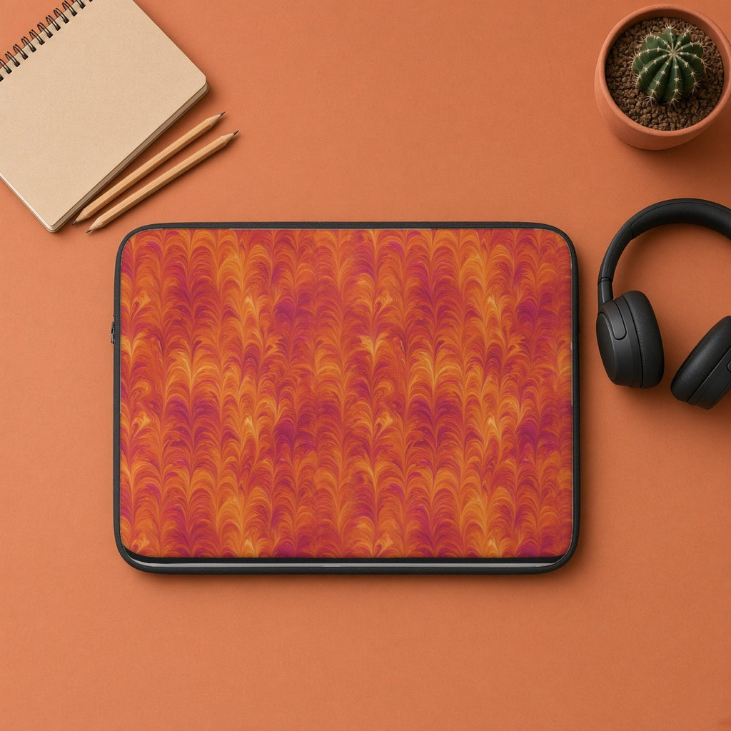 Sunset Feather Marbling laptop sleeve flat lay on terracotta with headphones and a notebook