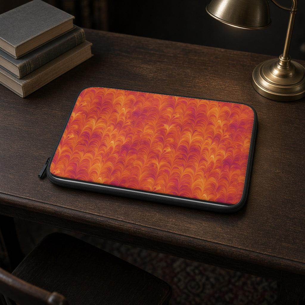 Sunset Feather Marbling laptop sleeve on a dark wood library desk with books and a lamp