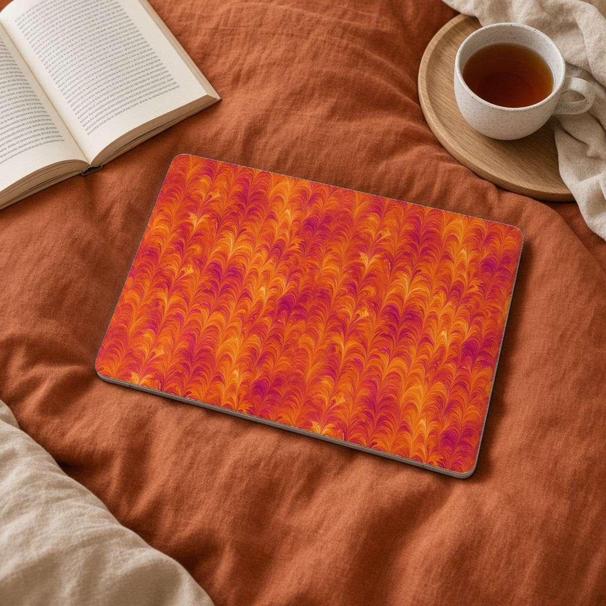 Sunset Feather Marbling matte MacBook case on a laptop on rust linen bedding