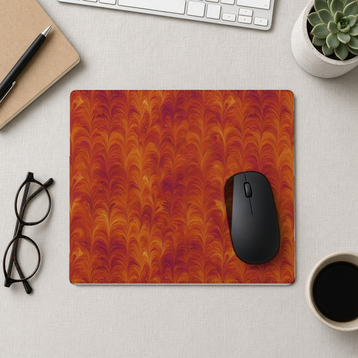Sunset Feather Marbling vegan leather mouse mat from above with a mouse, notebook and glasses