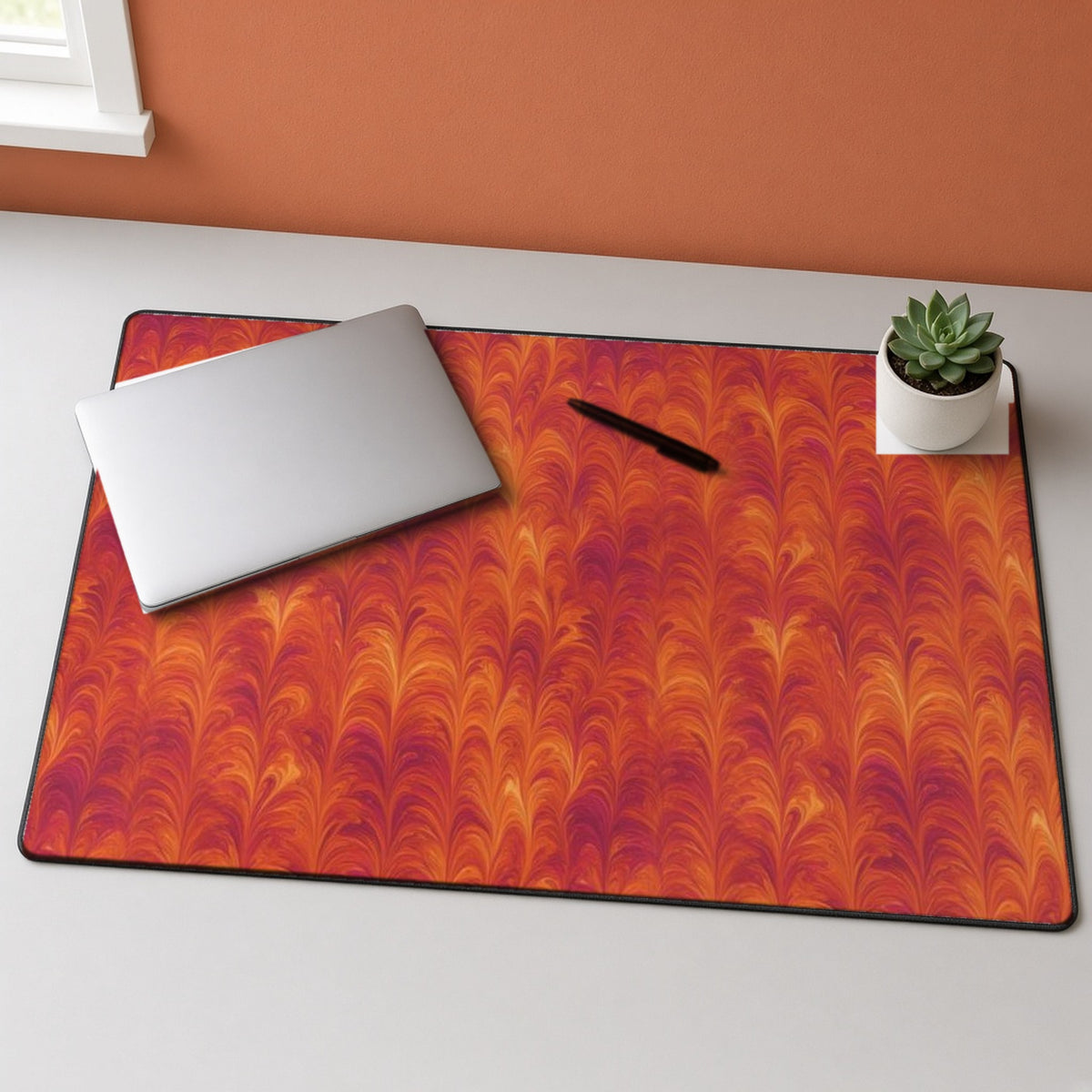 Sunset Feather Marbling desk mat on a grey desk with a laptop and a plant