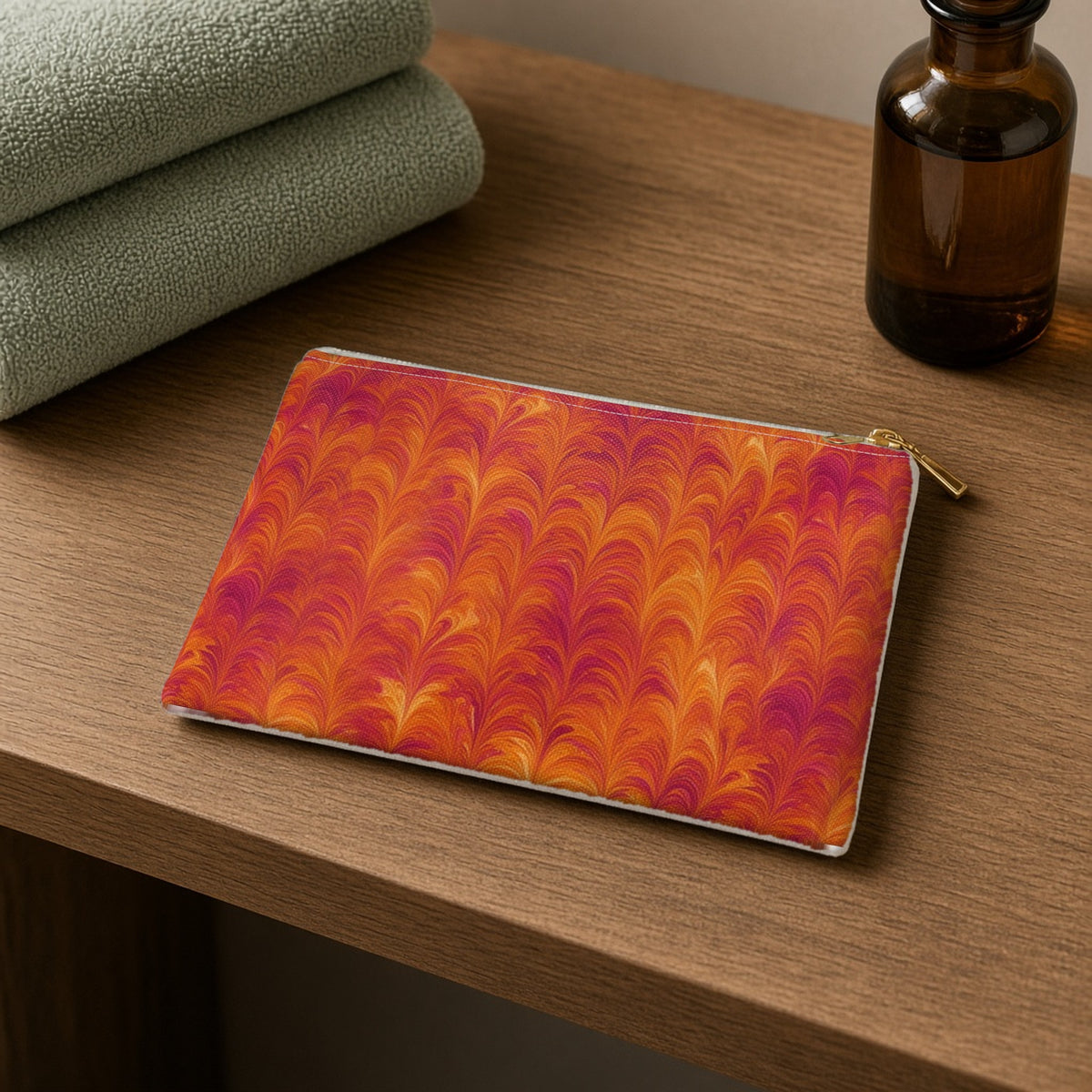 Sunset Feather Marbling zip accessory pouch on a wooden shelf with towels and an amber bottle