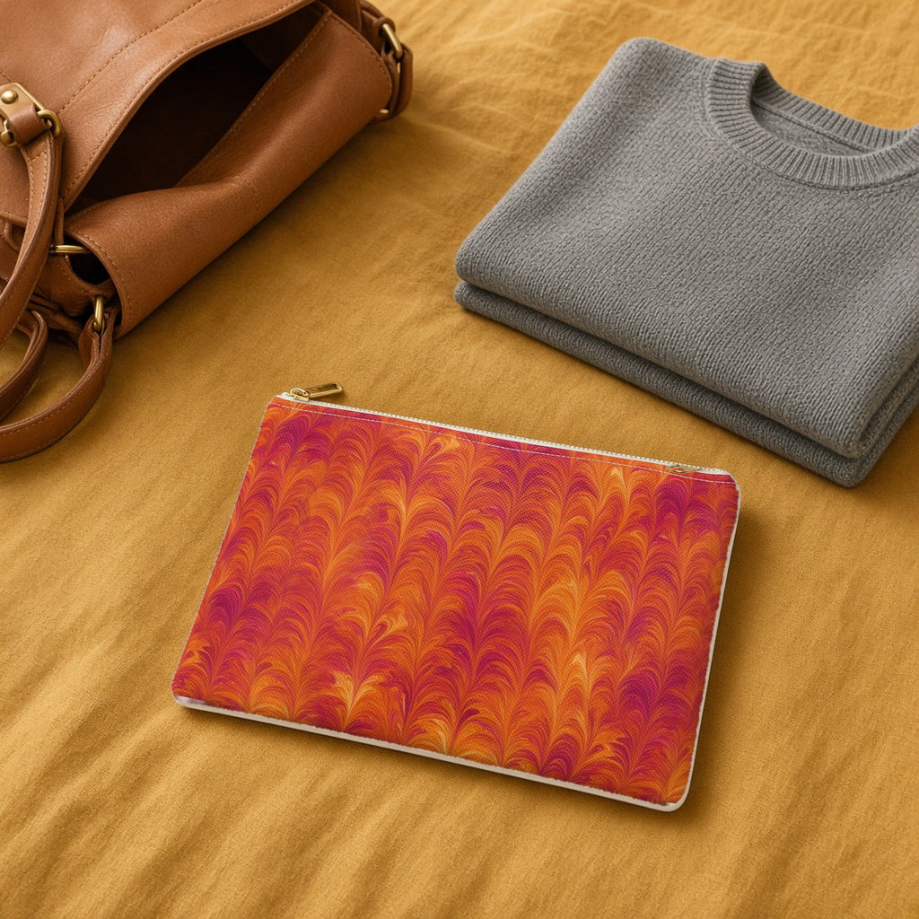Sunset Feather Marbling zip accessory pouch on a mustard bedspread with a leather bag and jumper