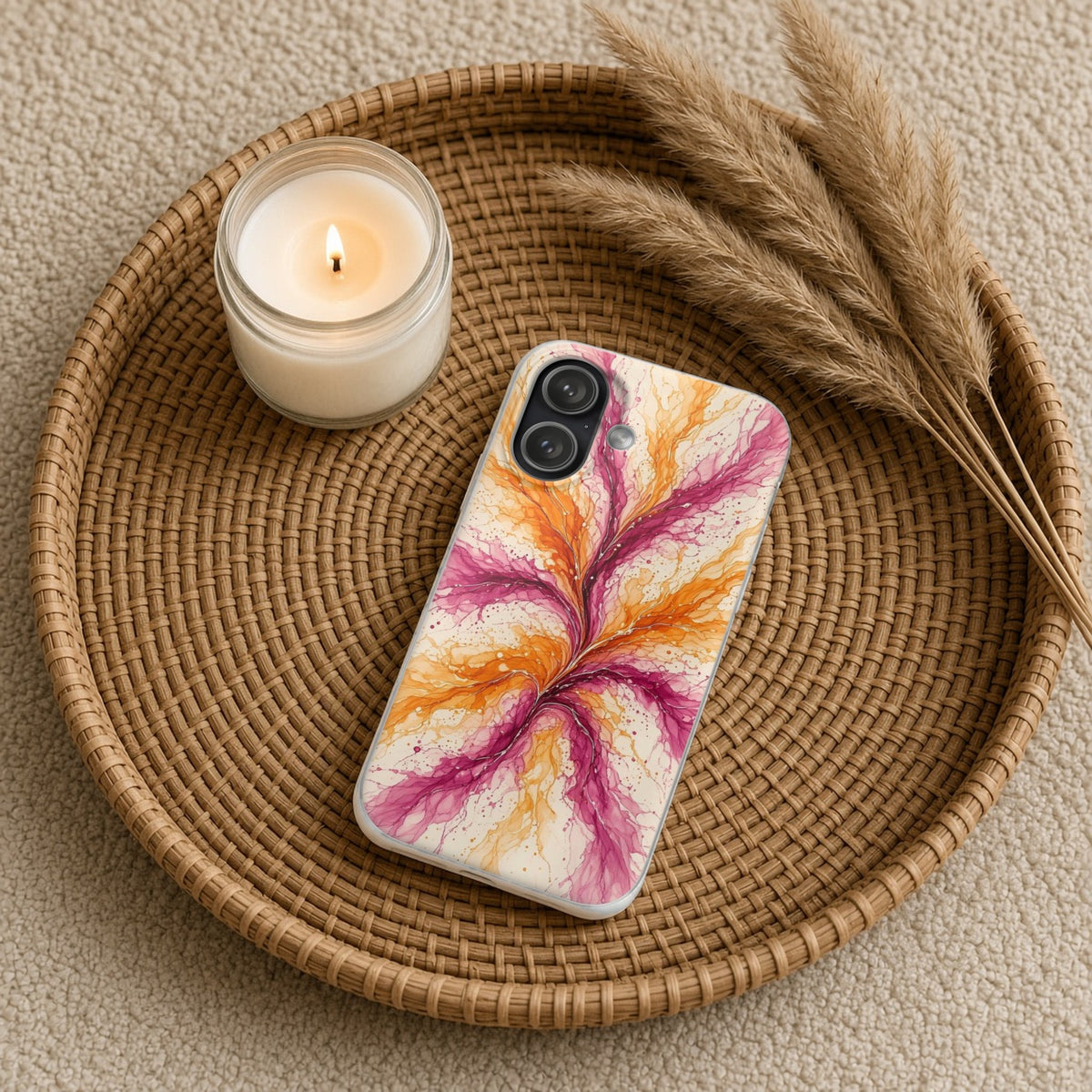 Sunset Ink Branches flexi phone case on a rattan tray with a candle and dried grasses