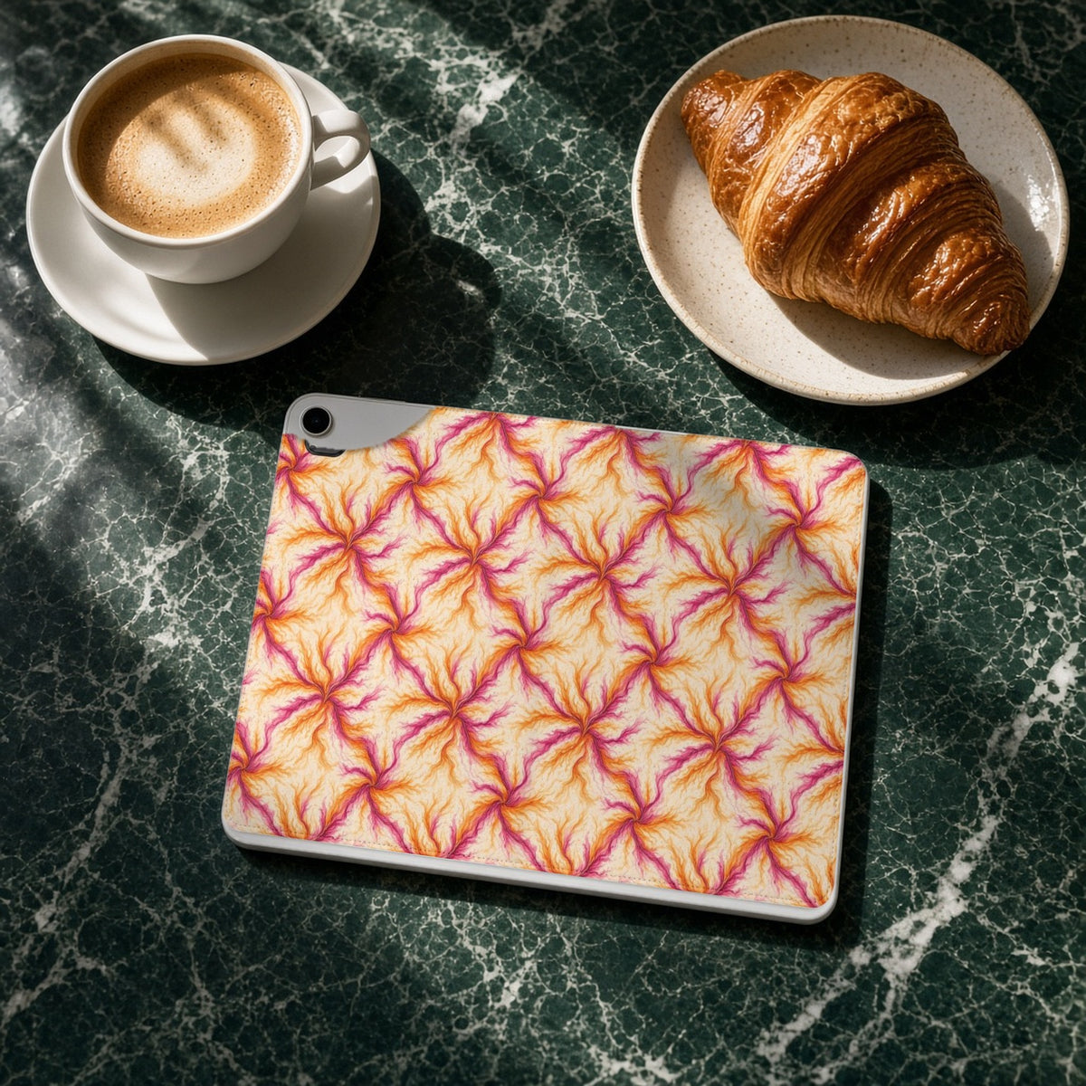 Sunset Ink Branches iPad folio case on a green marble cafe table with a cappuccino