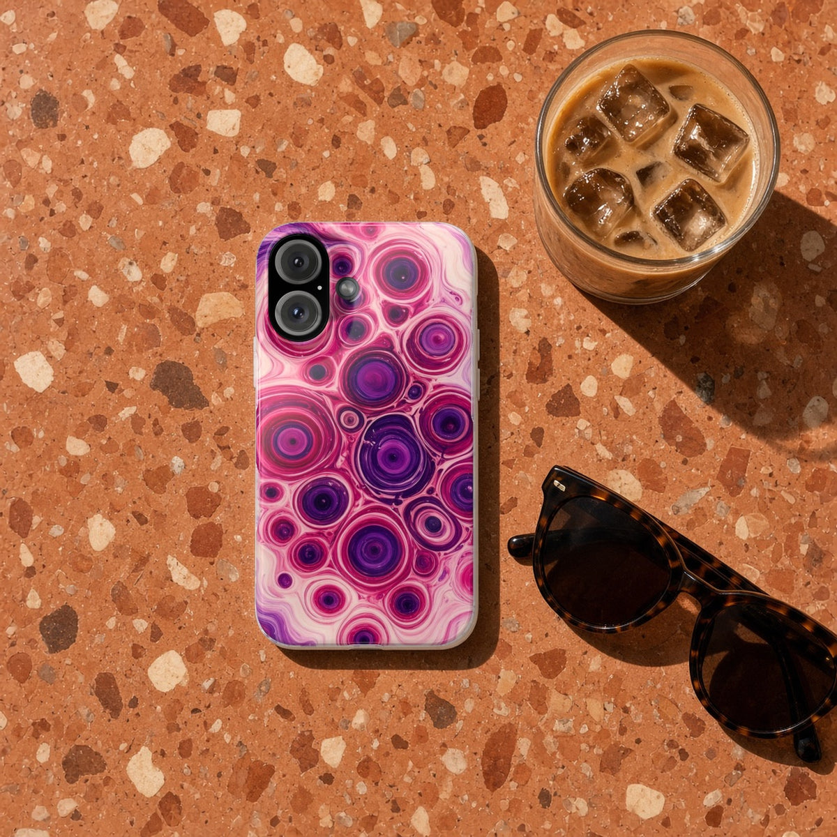 Berry Puddle Pour slim phone case on terrazzo with an iced coffee and sunglasses