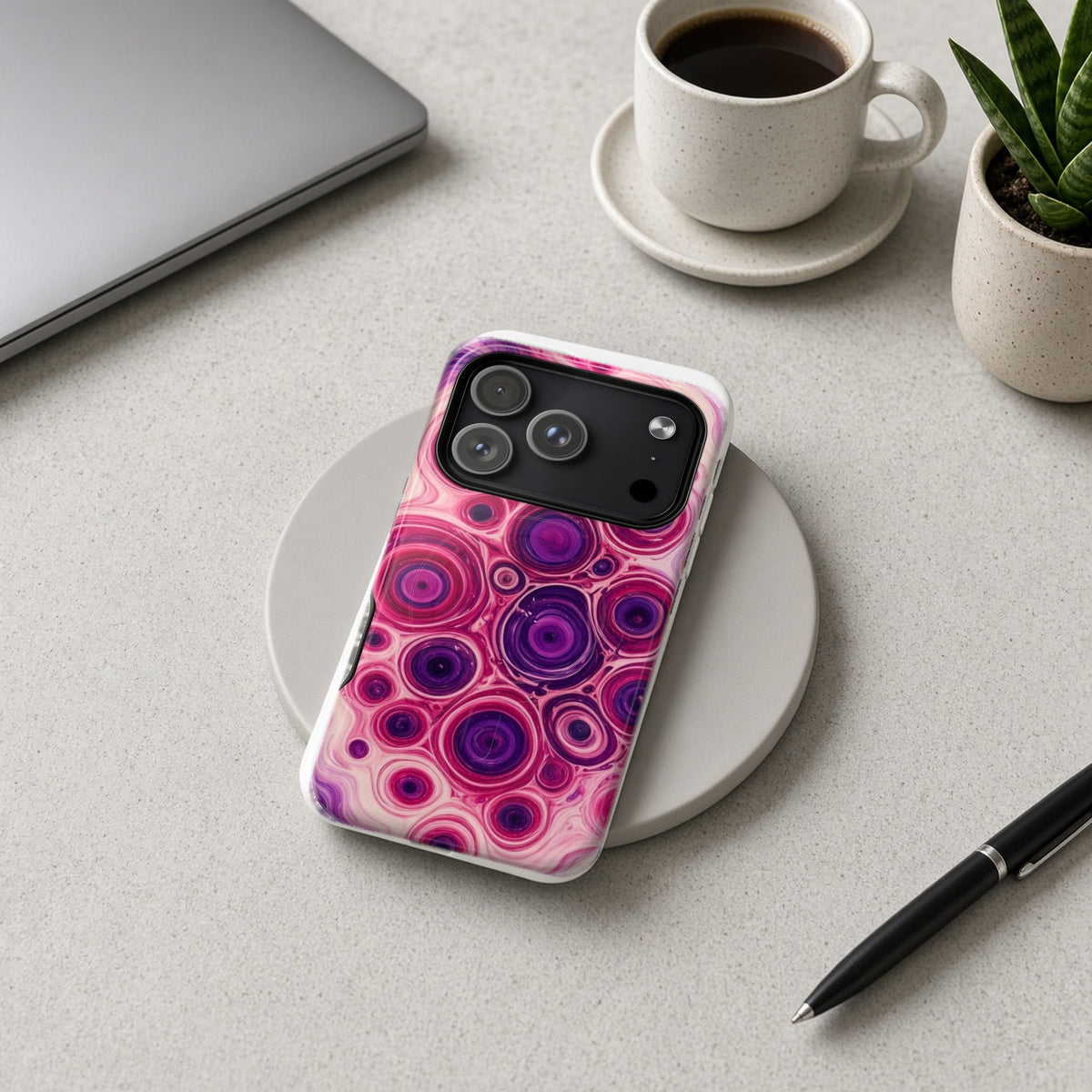 Berry Puddle Pour magnetic iPhone case on a wireless charging pad on a grey desk