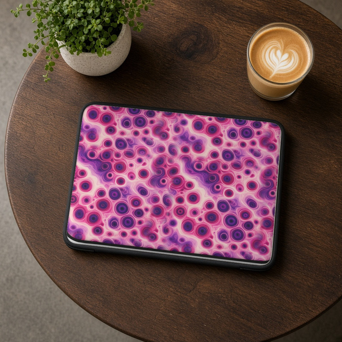 Berry Puddle Pour laptop sleeve on a round wooden cafe table with a latte