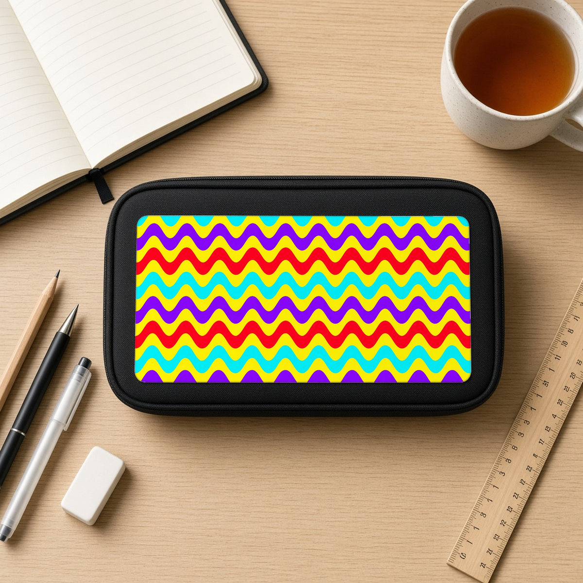 Big Ripple Chevrons pencil case on a wooden desk with notebook, pens and a cup of tea
