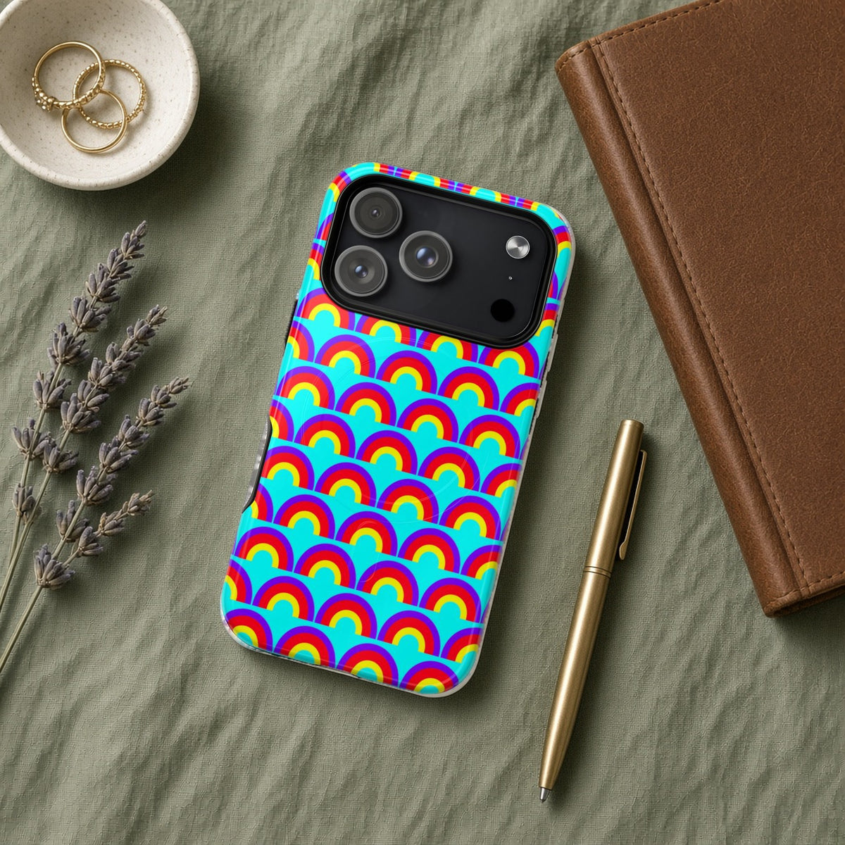 Chromatic Scallop Ripple magnetic iPhone case flat lay on sage linen with a notebook and pen