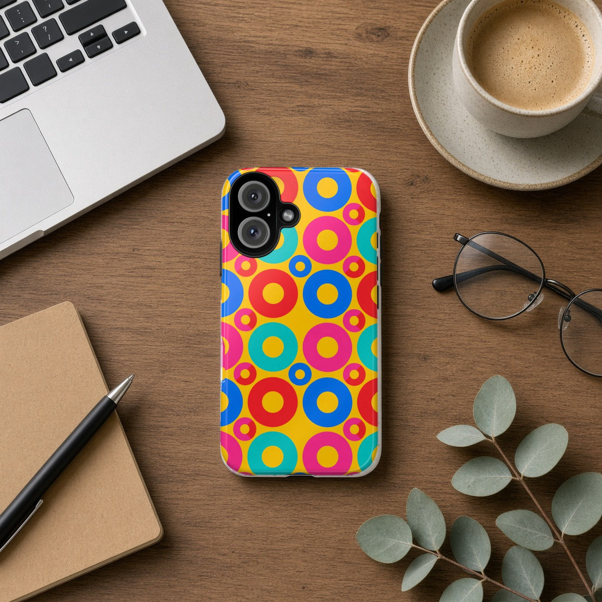 Big Ring Blocks tough phone case on a wooden desk beside a laptop, coffee and eucalyptus