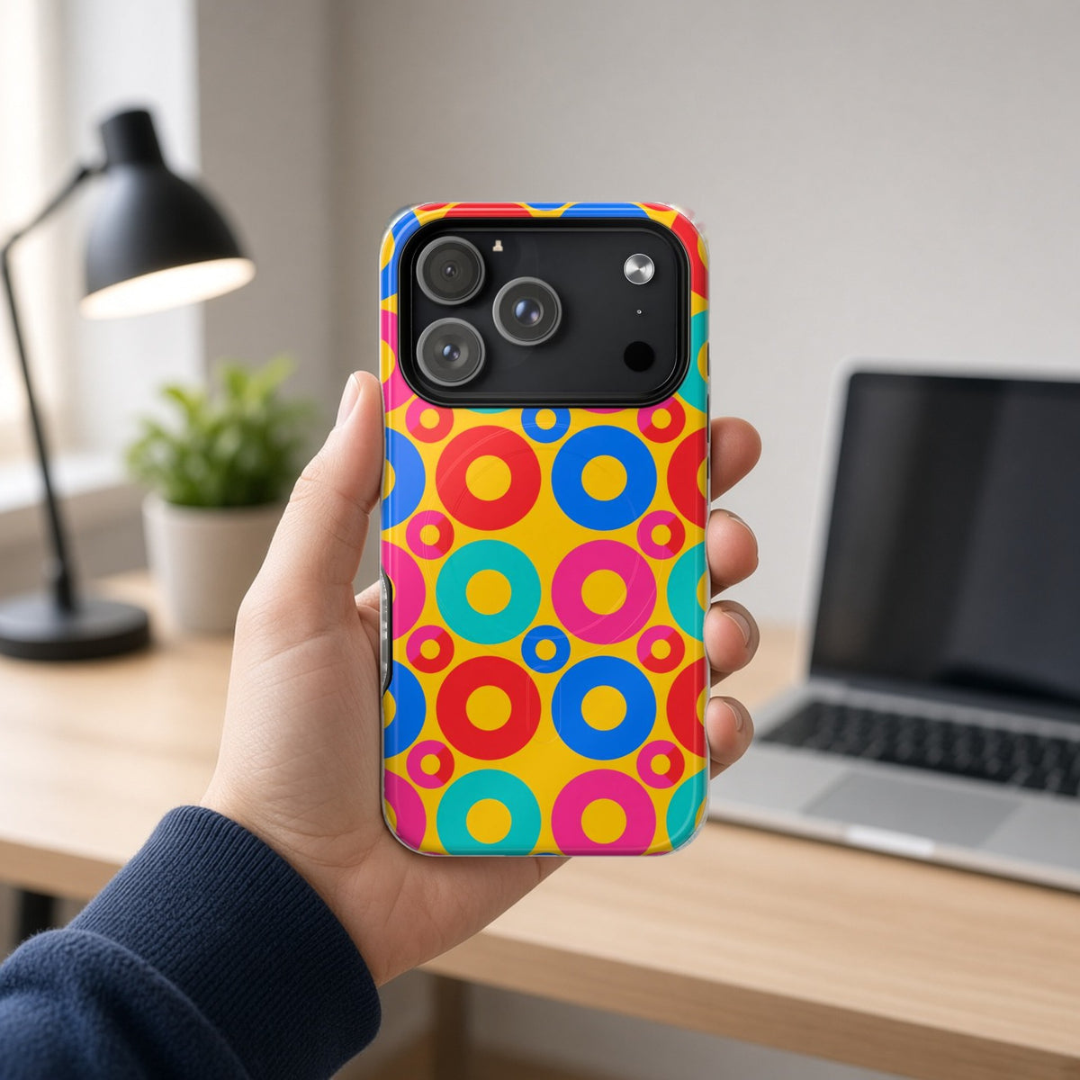 Hand holding the Big Ring Blocks magnetic iPhone case at a home office desk