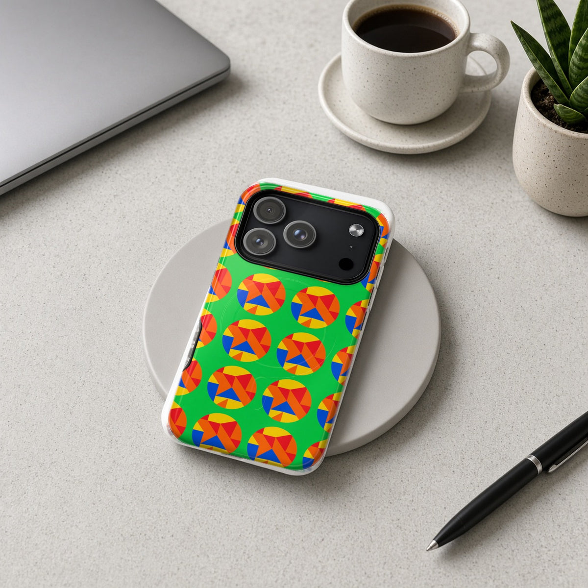 Broken Circle Planes magnetic iPhone case on a wireless charging pad on a grey desk