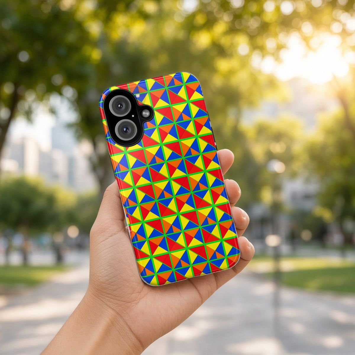 Hand holding the Split Square Fiesta tough phone case outdoors in a sunny park