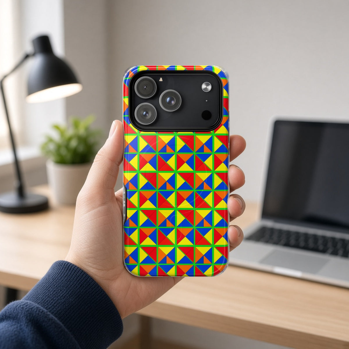 Hand holding the Split Square Fiesta magnetic iPhone case at a home office desk