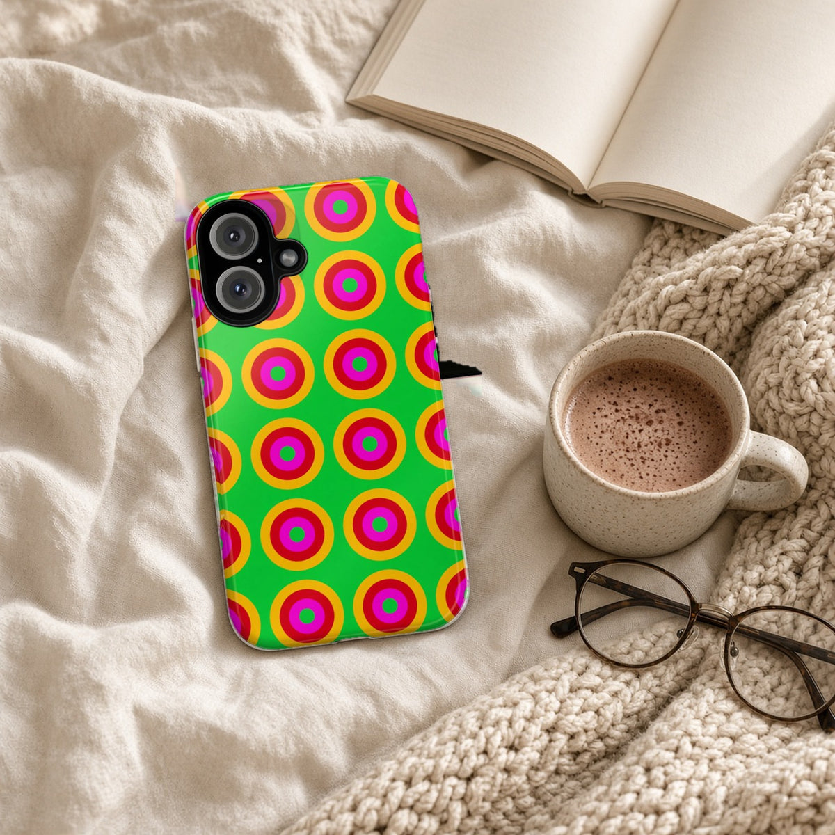 Giant Op-Art Jewel Rings tough phone case on a cosy knit blanket with a hot chocolate and glasses