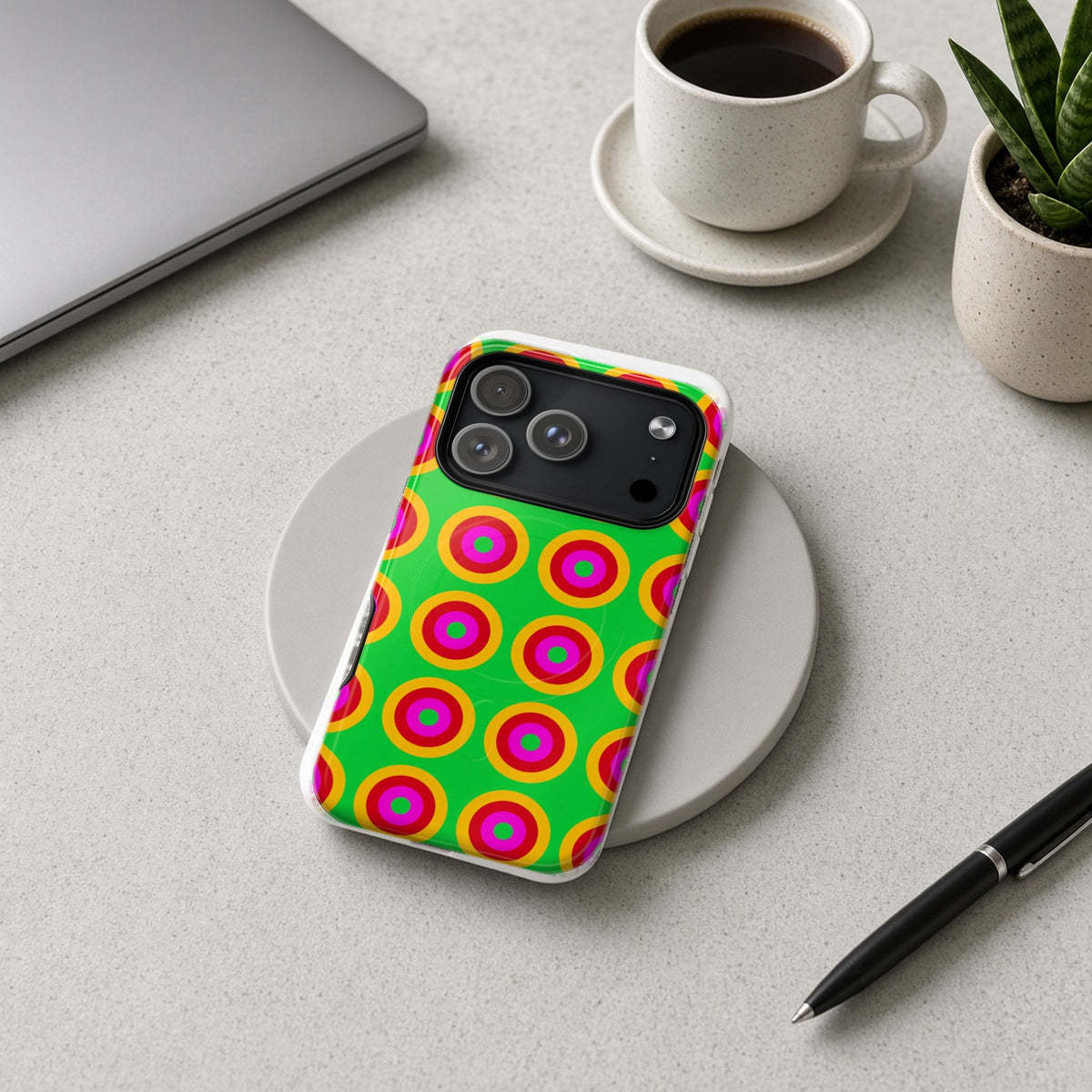 Giant Op-Art Jewel Rings magnetic iPhone case on a wireless charging pad on a grey desk