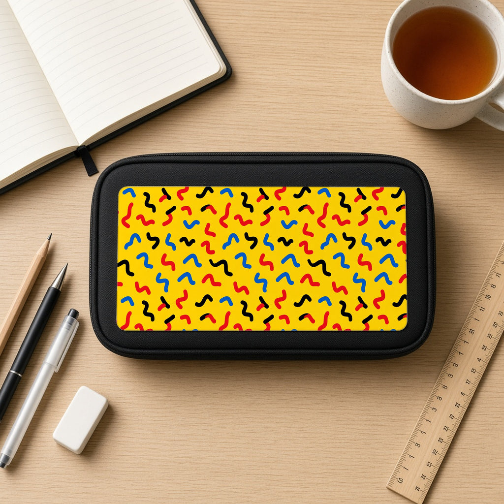 Squiggle Strokes Yellow pencil case on a wooden desk with notebook, pens and a cup of tea